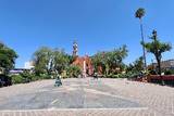 Plaza del Barrio de San Miguel vacía con cielo azul y de fondo se alcanza a ver la iglesia roja