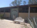 Se observa una aula de la escuela con una puerta de fierro viejo y oxidado, una banca de cemento vieja y rota