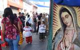 Se observa mural de la virgen de guadalupe y gente en la calle caminando