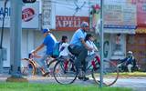 Se observa una avenida con un señor en bicicleta con dos niñas pequeñas